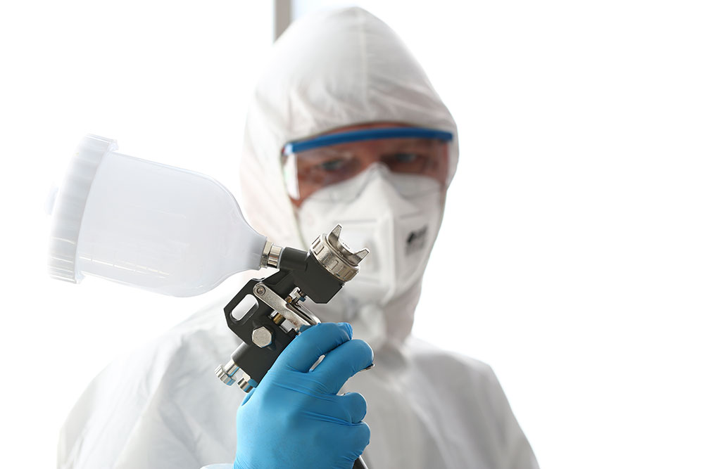 Worker wearing PPE holding spray paint gun. 